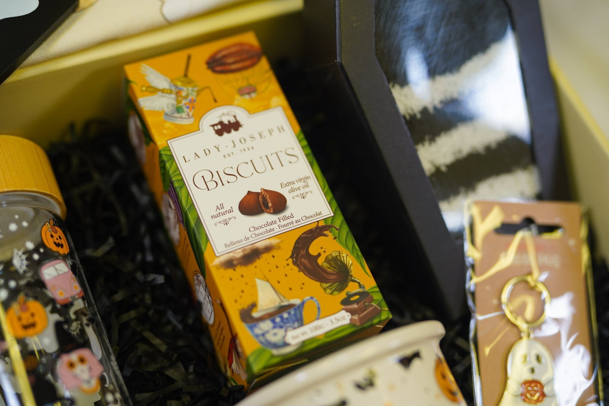 Cozy autumn Halloween treat box with mug, socks, biscuits, and spooky goodie